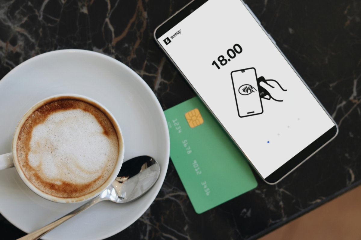 A cup of coffe with a credit card and a mobile phone, indicating the growth of a company